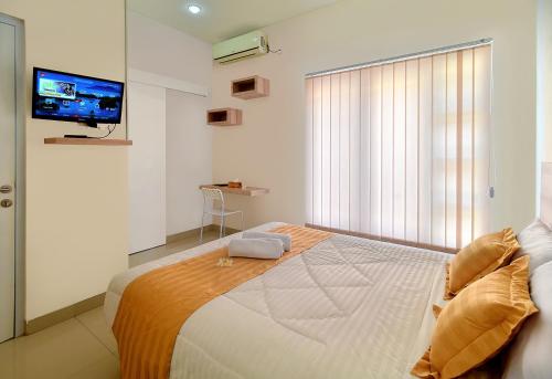 a bedroom with a large bed with a tv on the wall at Wika Bali Beach House in Jimbaran