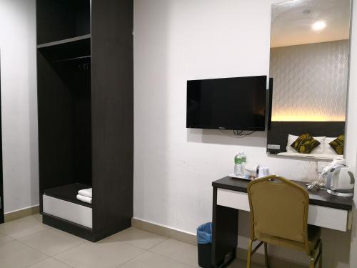 a room with a desk and a television on a wall at D'Metro Hotel in Shah Alam