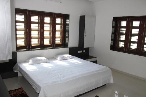 a white bed with two pillows in a room with windows at Classic Dineout in Gandhinagar