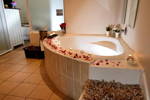 a bath tub in a bathroom with flowers around it at Riviera Hotel & Chalets in Velddrif