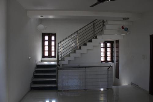 a staircase in a white room with two windows at Classic Dineout in Gandhinagar