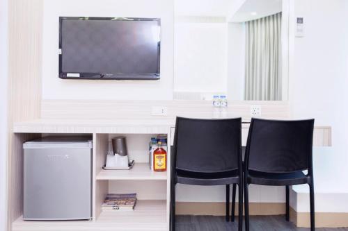 two chairs sitting at a bar with a television on a wall at The Charter House in Manila