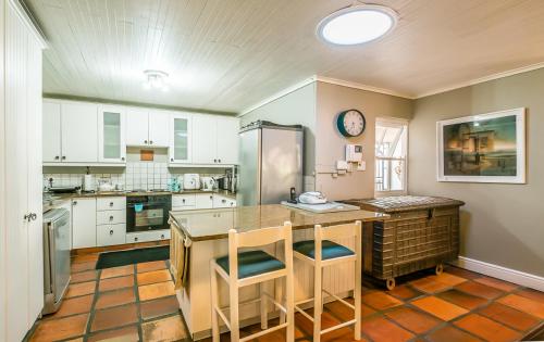 una cocina con armarios blancos y una barra con sillas en Inn-Style, en Ciudad del Cabo