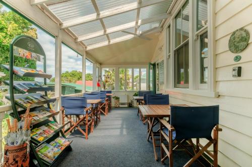 a conservatory with tables and chairs and windows at The Great Ponsonby Arthotel in Auckland