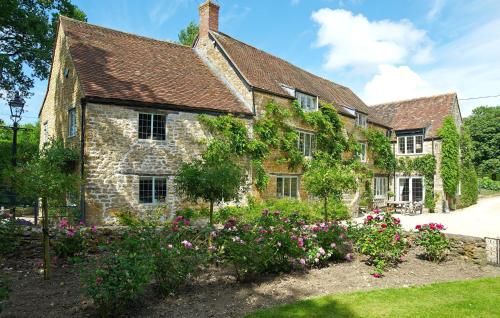 an old stone house with flowers in the yard at Hewletts Mill in Castle Cary
