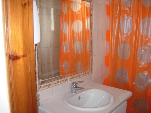 a bathroom with an orange shower curtain and a sink at Philippos Studios & Apartments in Kardamaina