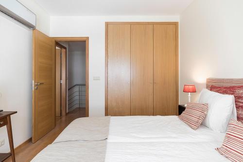 a bedroom with a white bed and a wooden cabinet at Flea Market Alfama House (Patio/Pool/AC/Garage) in Lisbon