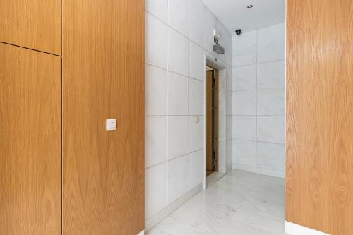 a hallway with white tile walls and a wooden door at Flea Market Alfama House (Patio/Pool/AC/Garage) in Lisbon