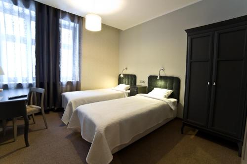 ポズナンにあるAvalis Apartamentyのベッド2台とデスクが備わるホテルルームです。