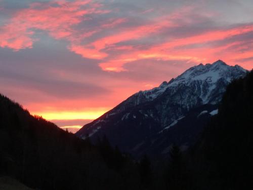 a sunset over a snow covered mountain at Ferienhaus am Wallnerhof in Flattach