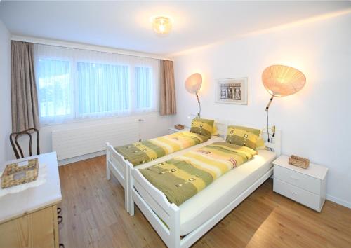 a white bedroom with two beds and a window at Haus Pyrola in Davos