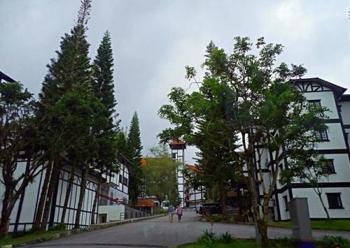 two people walking down a street next to buildings at 3 Rooms Apt@Greenhill Resort in Cameron Highlands