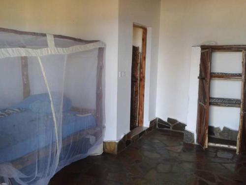 a bedroom with a bed and two windows at Mango Lodge MSAMBWENI in Kisimachande