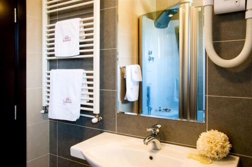 bagno con lavandino, specchio e asciugamani di Hotel Knezevina a Vranic