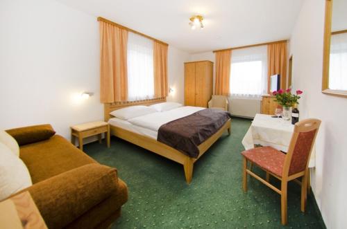 a bedroom with a bed and a couch and a table at Pension Parzer Pressbaum bei Wien in Pressbaum