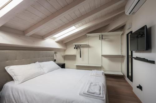 a bedroom with a white bed and a tv at Sant'Orsola Suites Apartments in Bologna