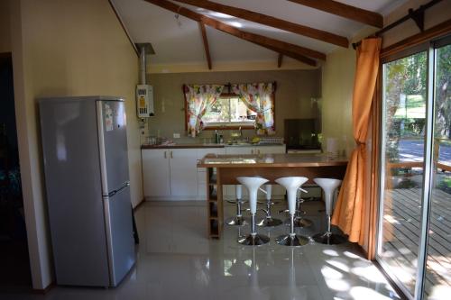 a kitchen with a refrigerator and a table with stools at Cabañas Kumelka in Villarrica