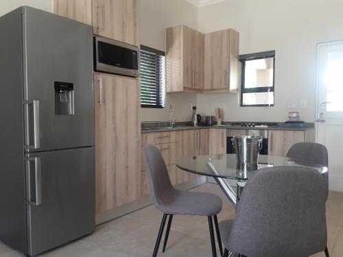 a kitchen with a table and a stainless steel refrigerator at Cottage@Somerset in Somerset West