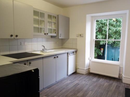 a kitchen with white cabinets and a window at Beechwood House in New Quay