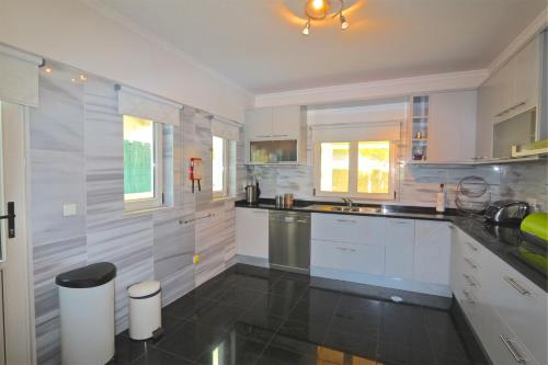 a kitchen with white cabinets and a black floor at Villa Heloise 139 - Clever Details in Vilamoura