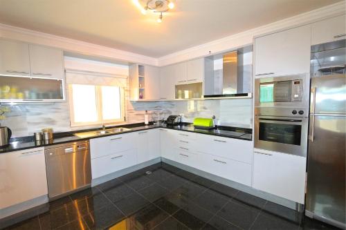 a kitchen with white cabinets and stainless steel appliances at Villa Heloise 139 - Clever Details in Vilamoura