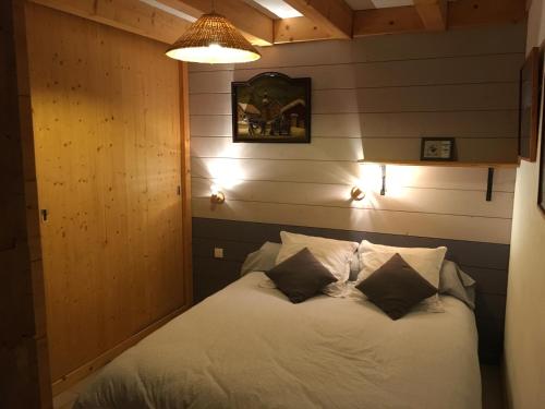 a bedroom with a white bed with two pillows at La Planque des Marmottes in Servoz