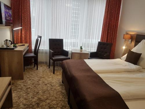 a hotel room with a bed and a desk and chairs at Park Hotel in Bad Zwischenahn