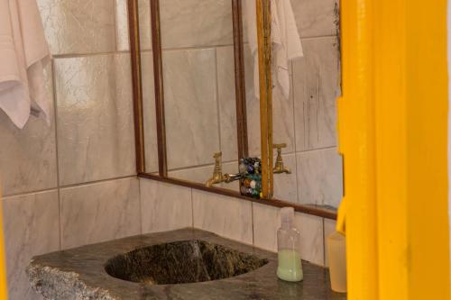 uma casa de banho com um lavatório, uma janela e uma garrafa de sabonete. em Pouso da Passagem B&B em Mariana
