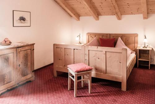サン・ロレンツォ・ディ・セバートにあるMessnerwirt Onachのベッドルーム1室(ベッド1台、スツール、椅子付)
