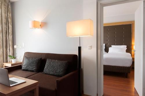 a living room with a couch and a bed at Relais Spa Val d'Europe in Chessy