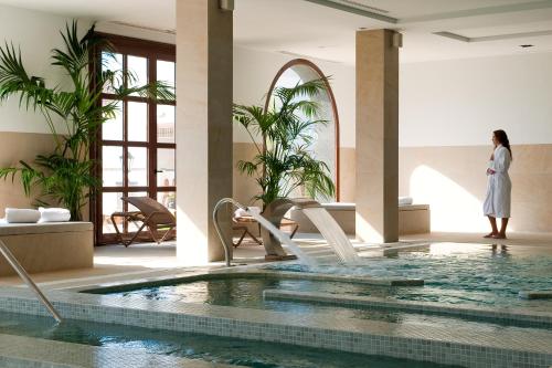 a woman standing next to a pool in a hotel at Hotel Hacienda del Conde Meliá Collection Golf & Spa - Adults Only in Buenavista del Norte