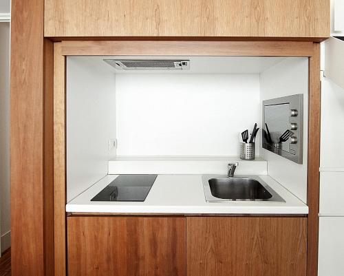 a kitchen counter with a sink and a mirror at BB Hotels Aparthotel Desuite in Milan