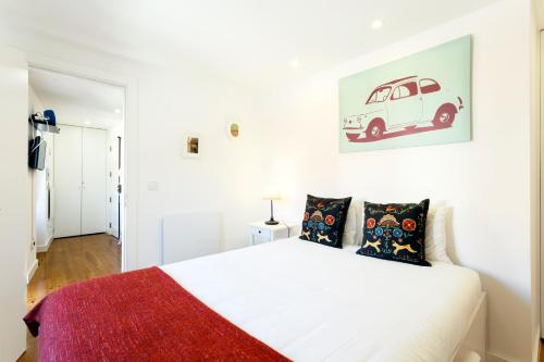 リスボンにあるWHome | Paz Downtown Apartment #3の白いベッド1台、壁に車の写真が備わるベッドルーム1室