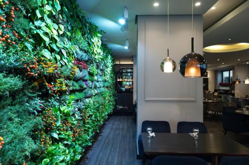 a green wall in a restaurant with tables and chairs at Amberton Cathedral Square Hotel Vilnius in Vilnius