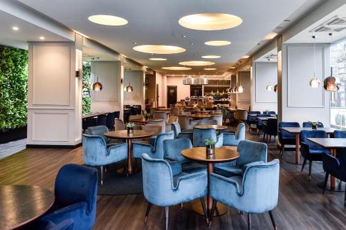 a restaurant with blue chairs and tables and tablesktop at Amberton Cathedral Square Hotel Vilnius in Vilnius