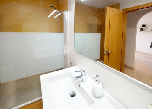 a bathroom with a white sink and a mirror at La Perla: Sea View and Pool (family apartment) in El Médano