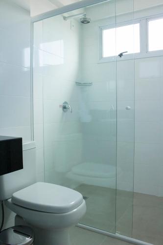 a bathroom with a toilet and a glass shower at Hotel Real Executive in Aparecida de Goiania