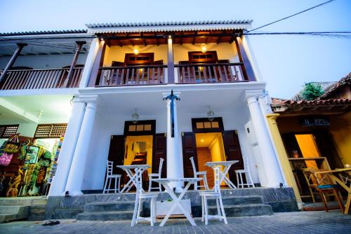 Un edificio blanco con mesas y sillas delante. en Bastille, en Galle