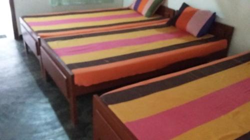 three beds are lined up in a room at Inn On The Bay in Pasikuda