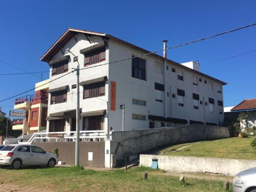 a white building with cars parked in front of it at Hotel Acuarium in Villa Gesell