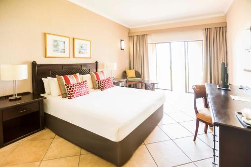 a hotel room with a large bed and a desk at Avani Pemba Beach Hotel in Pemba