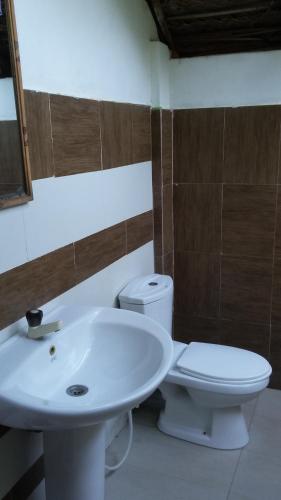 a bathroom with a white sink and a toilet at Inn On The Bay in Pasikuda