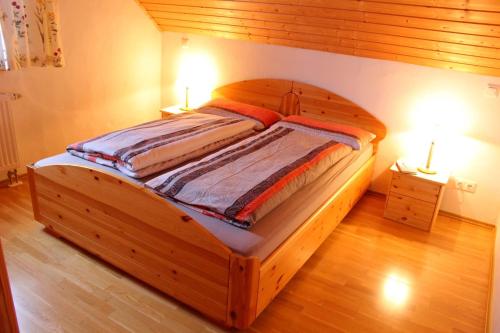 een houten bed in een slaapkamer met 2 lampen op tafels bij Appartement Landelijke Star in Winterberg