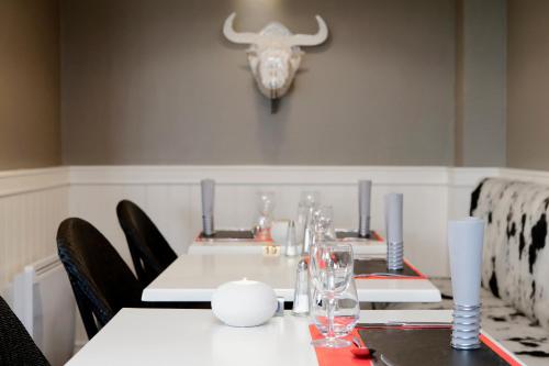a dining room with tables and chairs and a cow skull on the wall at ibis Dole Sud Choisey in Dole