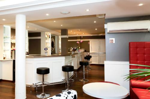 a kitchen with bar stools and a red couch at ibis Dole Sud Choisey in Dole