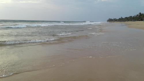 a sandy beach with waves coming in from the ocean at Guruwaththa Eco Lodge in Hikkaduwa
