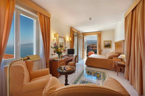 a hotel room with a bed and chairs and windows at Hotel Continental in Sorrento
