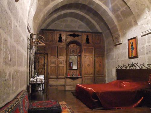 a bedroom with a red bed in a stone room at Kapadokya Ihlara Konakları Otel Konak Odaları in Guzelyurt