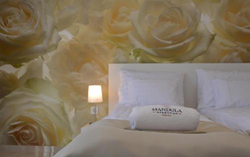 a bedroom with a bed with roses on the wall at Mandula Apartman in Cegléd