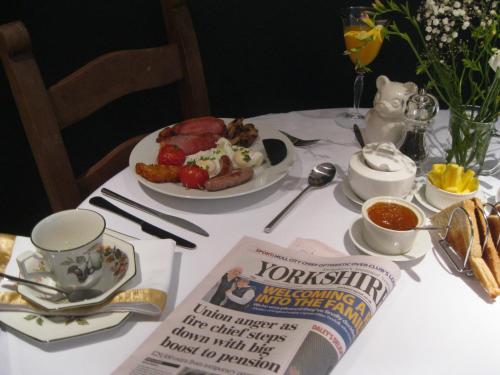 una mesa con un plato de comida y un periódico en Teardrop Cottage en Knaresborough